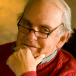 Retrato de Frederick Buechner con gafas y jersey rojo